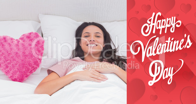 Composite image of woman lying in her bed next to a pink heart p