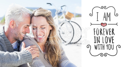 Composite image of happy couple sitting on the sand together