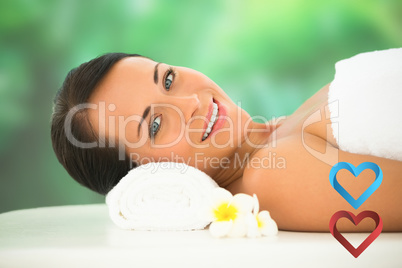 Composite image of beautiful brunette relaxing on massage table