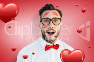 Composite image of geeky hipster with kisses on his face