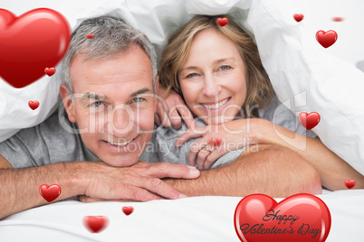 Composite image of loving couple under the duvet