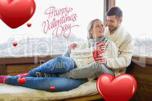 Composite image of loving couple in winter wear with cups agains