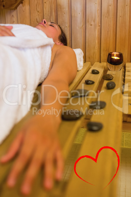 Composite image of calm brunette woman lying in a sauna