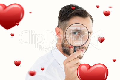 Composite image of geeky businessman looking through magnifying