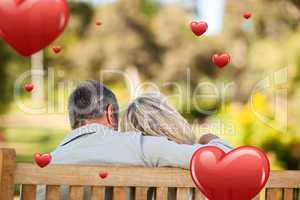 Composite image of elderly couple sitting on the bench with thei