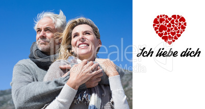 Composite image of carefree couple hugging in warm clothing