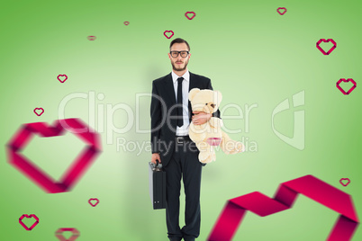 Composite image of geeky businessman holding briefcase and teddy