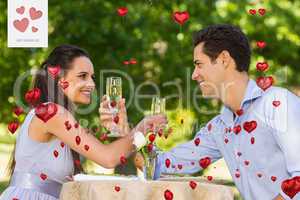 Composite image of couple with champagne flutes sitting at outdo