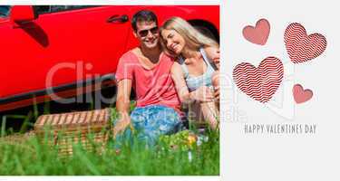 Composite image of smiling couple sitting on the grass having pi