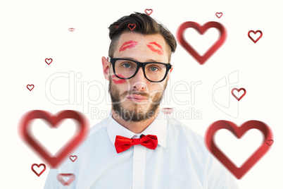 Composite image of geeky hipster with kisses on his face