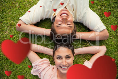 Composite image of two friends smiling while lying head to head