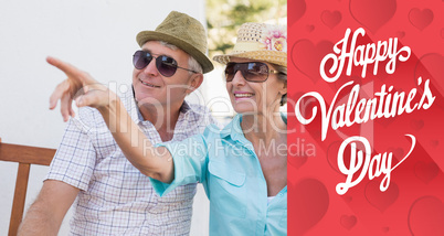 Composite image of happy mature couple sitting on bench in the c