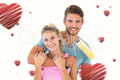 Composite image of young couple hugging and holding paint roller