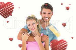 Composite image of young couple hugging and holding paint roller