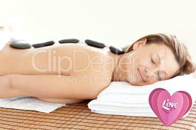 Composite image of radiant woman with hot stones on her back