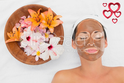 Composite image of smiling brunette getting a mud treatment faci