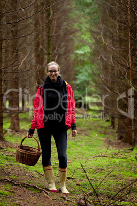 young woman collecting mushrooms in forest