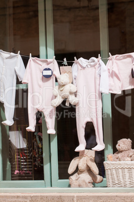 baby clothing and teddy bear in window