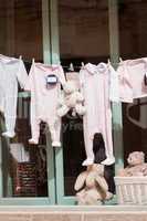 baby clothing and teddy bear in window