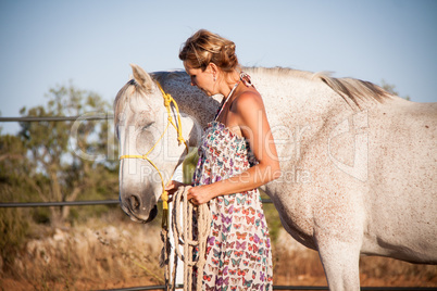 young woman walking a road with horse