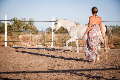 young woman walking a road with horse