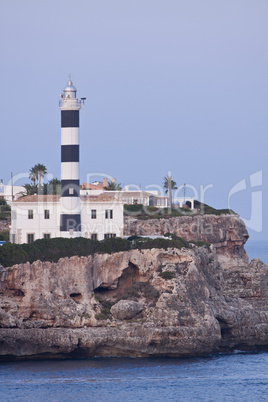 white lighthouse on rocks in the sea ocean water sky blue