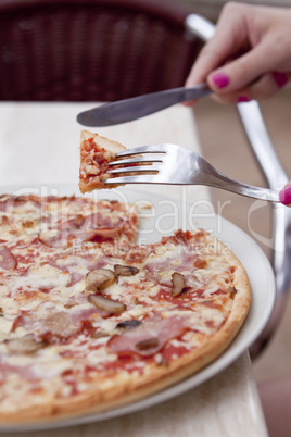 young woman is eating a pizza in restaurant