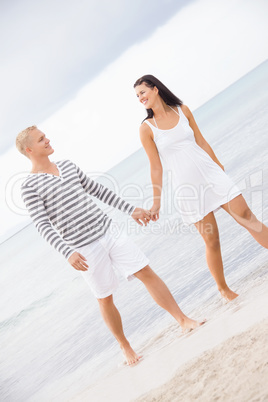 Couple holding hands while walking on the beach