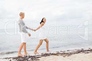 Couple holding hands while walking on the beach