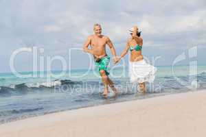 young happy couple walking on beach sunset holiday
