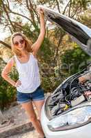 Woman inspecting her car engine after a breakdown