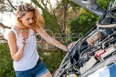 Woman inspecting her car engine after a breakdown