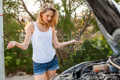 Woman inspecting her car engine after a breakdown