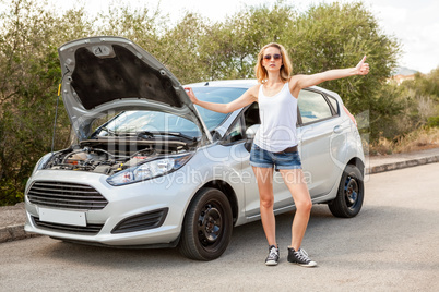 Woman inspecting her car engine after a breakdown