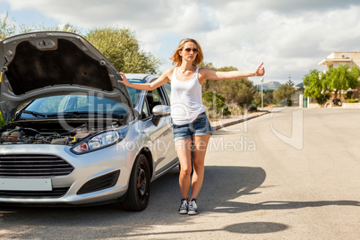 Woman inspecting her car engine after a breakdown