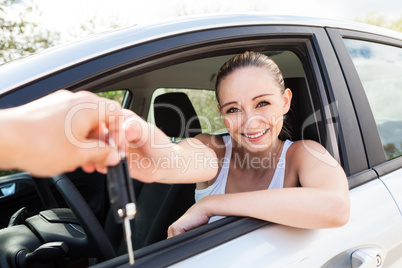 young smiling woman sitting in car taking key