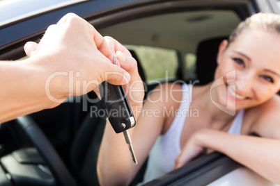 young smiling woman sitting in car taking key