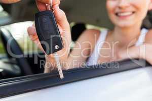 young smiling woman sitting in car taking key