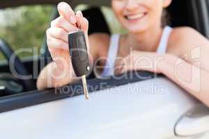 young smiling woman sitting in car taking key