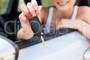 young smiling woman sitting in car taking key