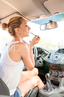 Beautiful woman applying makeup in the car