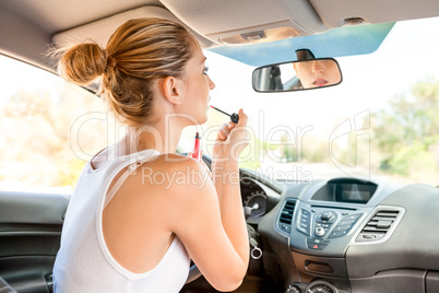 Beautiful woman applying makeup in the car