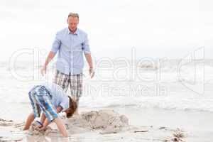 father and sons on the beach playing in the sand