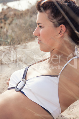 happy young woman sitting in sand dunes beach