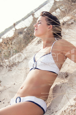 happy young woman sitting in sand dunes beach
