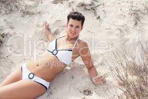 happy young woman sitting in sand dunes beach