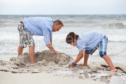 father and sons on the beach playing in the sand