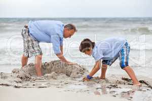 father and sons on the beach playing in the sand