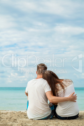 romantic young couple sitting on the beach in summer