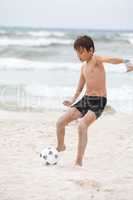 happy little boy  playing football on beach summer